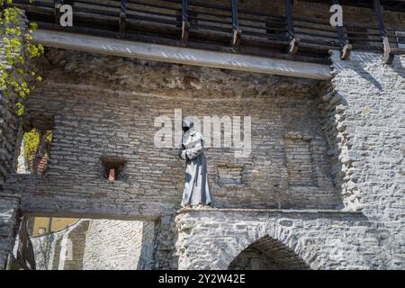 Tallinn, Estonie - 8 mai 2024 : une statue solitaire d'un moine sans visage surplombe le paysage urbain historique de Tallinn. Les mains du moine sont serrées dans la prière Banque D'Images