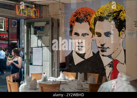 Prince Harry et Prince William ensemble, leurs portraits peints sur le mur d'un restaurant à Brick Lane. Vu à travers la fenêtre dans l'intérieur. Des gens qui passent. East End de Londres, Angleterre juin 2013 2010 Royaume-Uni HOMER SYKES Banque D'Images