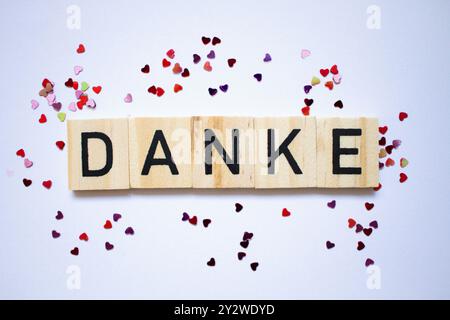 Carte de remerciement en langue allemande, texte danke, petits coeurs minuscules brillants autour des lettres scrablle Banque D'Images