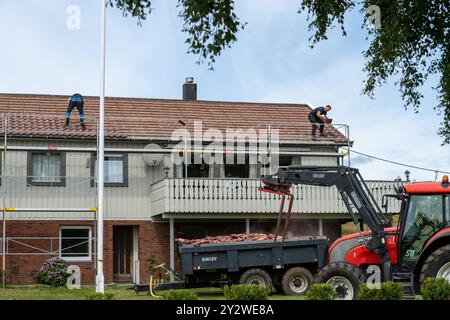 Lindesnes, Norvège - 09 août 2022 : constructeurs enlevant les tuiles rouges d'une maison Banque D'Images