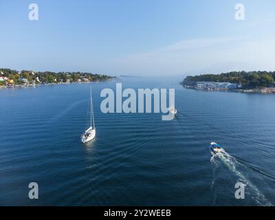 Voiliers et un bateau naviguant sur la mer avec le brouillard matinal roulant sur une île au début de l'automne, Dalarö, archipel suédois, Suède. Banque D'Images