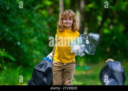 Enfant dans des gants en caoutchouc avec sac poubelle nettoyer les ordures sur la forêt en plein air. ECO, conservation de l'environnement. Recycler la pollution. Enfant garçon ramassant les ordures a Banque D'Images