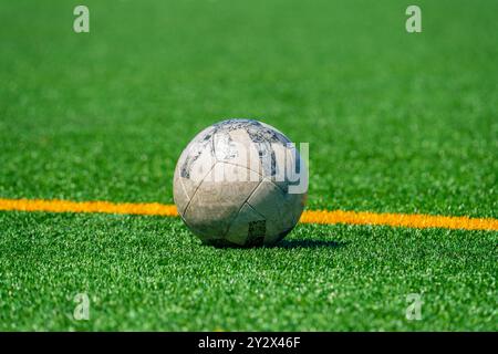 Un ballon de football reposant sur un terrain vert, avec une ligne jaune vif coupant la scène en diagonale, créant un contraste saisissant entre le b. Banque D'Images