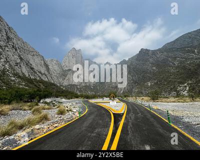 Route panoramique menant vers des montagnes imposantes sous un ciel partiellement nuageux dans le parc la Huasteca, Monterrey, Mexique Banque D'Images