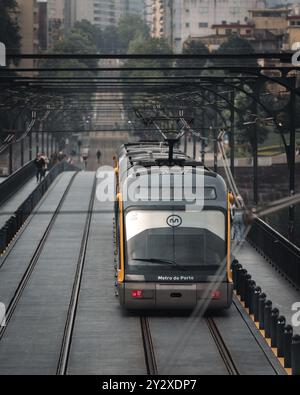 Metro do Porto tram voyageant sur un pont à Porto, Portugal avec des bâtiments de la ville en arrière-plan Banque D'Images