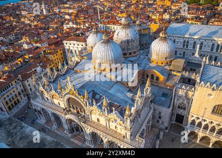 La magnifique basilique Saint-Marc se dresse fièrement sur la Piazza San Marco, présentant son architecture complexe et ses dômes contre un coucher de soleil vibrant à Venise, attirant les visiteurs et capturant les cœurs. Banque D'Images