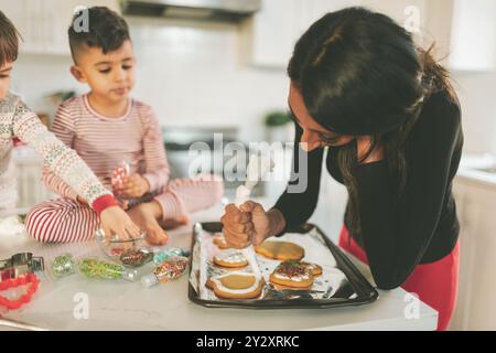 Une mère et des enfants préparant et décorant des biscuits de Noël Banque D'Images