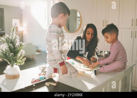 Une mère et des enfants préparant et décorant des biscuits de Noël Banque D'Images