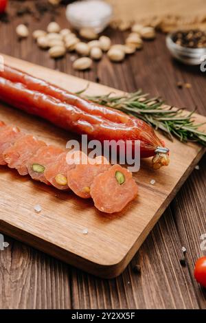 Saucisse tranchée avec pistaches sur planche de bois, idéale pour les présentations alimentaires et les affichages gastronomiques Banque D'Images