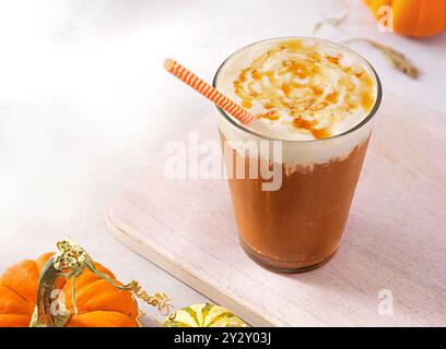 Latte glacé à la citrouille épicée garni de crème fouettée végétalienne et de sirop d'érable Banque D'Images