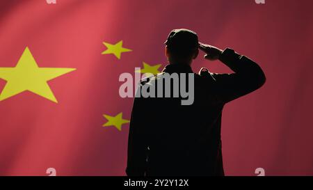 Membre de l'armée chinoise faisant un geste de salutation de la main vers le drapeau chinois dans le centre de commandement, montrant du respect. Unité militaire en uniforme au service du Parti communiste chinois, faisant des gestes d'honneur, caméra B. Banque D'Images