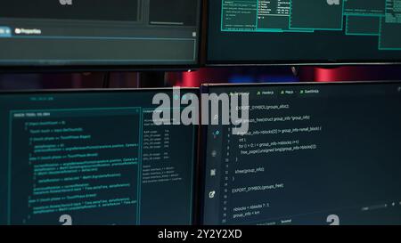 Gros plan de l'interface du logiciel sur les écrans d'ordinateur montrant le code de développeur en cours d'exécution dans la tanière vide des criminels. Piratage du script de programmation de malware sur les moniteurs dans la base souterraine Banque D'Images