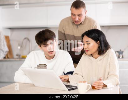 Une famille amicale regarde quelque chose ensemble sur Internet ou des chats vidéo via un ordinateur portable Banque D'Images