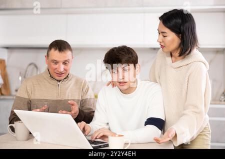 Une famille amicale regarde quelque chose ensemble sur Internet ou des chats vidéo via un ordinateur portable Banque D'Images