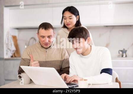 Une famille amicale regarde quelque chose ensemble sur Internet ou des chats vidéo via un ordinateur portable Banque D'Images