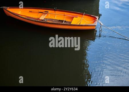 Petit bateau orange amarré sur une rivière sans personne Banque D'Images