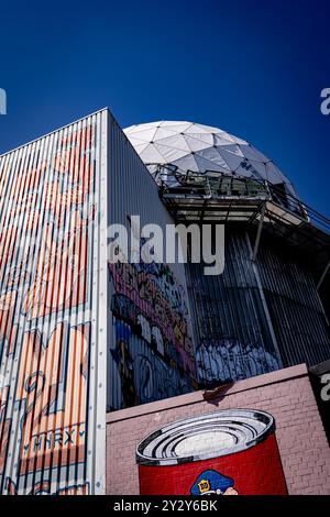 Une photo artistique d'un bâtiment avec des graffitis vibrants et un dôme géodésique sur un ciel bleu clair. Banque D'Images