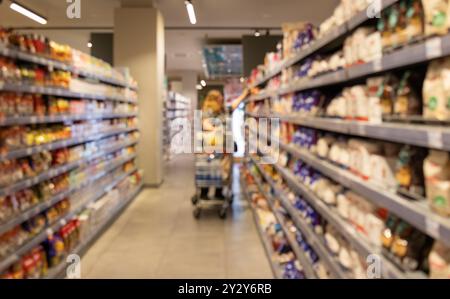 Étagères abstraites floues dans un supermarché. Décor flou à l'intérieur de l'épicerie, large gamme de marchandises, allée de supermarché dynamique, environnement de magasinage Banque D'Images