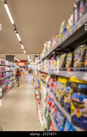 Étagères abstraites floues dans un supermarché. Décor flou à l'intérieur de l'épicerie, large gamme de marchandises, allée de supermarché dynamique, environnement de magasinage Banque D'Images