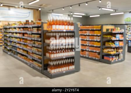 Étagères abstraites floues dans un supermarché. Décor flou à l'intérieur de l'épicerie, large gamme de marchandises, allée de supermarché dynamique, environnement de magasinage Banque D'Images