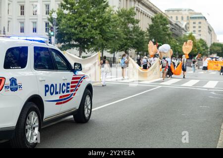 Washington DC, USA - 19/2024 : une voiture de police est garée sur le bord de la route. Un groupe de personnes marche dans la rue Banque D'Images