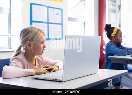 À l'école, fille utilisant un ordinateur portable en classe, en se concentrant sur les activités d'apprentissage Banque D'Images