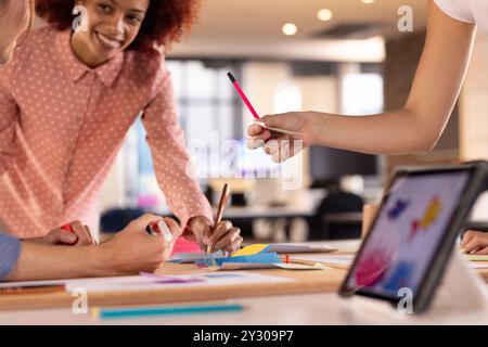 Collaboration sur un projet d'écriture créative, femmes multiraciales utilisant la tablette et les marqueurs dans le bureau Banque D'Images