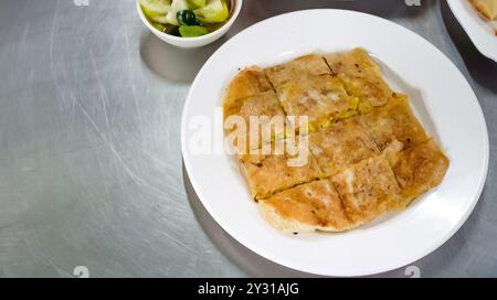 Poulet Mataba sur une assiette blanche et un bol de sauce à tremper à côté. Tout ce menu est sur la table de surface inoxydable. Banque D'Images