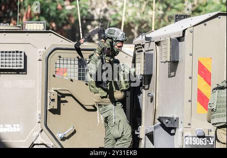 Tubas, Palestine. 11 septembre 2024. Un soldat israélien monte à bord de son véhicule lors d'un raid dans une maison palestinienne lors du raid sur la ville de Tubas. Un raid militaire israélien de grande envergure contre la ville de Tubas, dans le nord de la Cisjordanie occupée, a permis de tuer cinq Palestiniens dans une frappe aérienne et les forces ont encerclé un hôpital palestinien et empêché le personnel médical de transporter des patients à destination et en provenance de celui-ci. Crédit : SOPA images Limited/Alamy Live News Banque D'Images