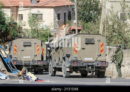 Tubas, Palestine. 11 septembre 2024. Des véhicules militaires israéliens, dont des soldats, bloquent l'entrée de la ville de Tubas lors du raid sur la ville de Tubas. Un raid militaire israélien de grande envergure contre la ville de Tubas, dans le nord de la Cisjordanie occupée, a permis de tuer cinq Palestiniens dans une frappe aérienne et les forces ont encerclé un hôpital palestinien et empêché le personnel médical de transporter des patients à destination et en provenance de celui-ci. Crédit : SOPA images Limited/Alamy Live News Banque D'Images