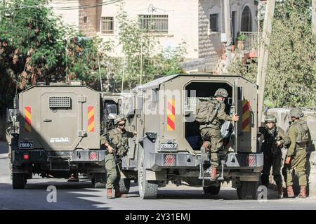 Tubas, Palestine. 11 septembre 2024. Les soldats israéliens sortent de leurs véhicules lors d'un raid sur une maison palestinienne pendant le raid sur la ville de Tubas. Un raid militaire israélien de grande envergure contre la ville de Tubas, dans le nord de la Cisjordanie occupée, a permis de tuer cinq Palestiniens dans une frappe aérienne et les forces ont encerclé un hôpital palestinien et empêché le personnel médical de transporter des patients à destination et en provenance de celui-ci. Crédit : SOPA images Limited/Alamy Live News Banque D'Images