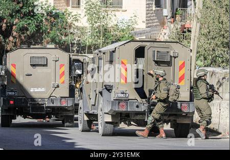 Tubas, Palestine. 11 septembre 2024. Les soldats israéliens sortent de leurs véhicules lors d'un raid sur une maison palestinienne pendant le raid sur la ville de Tubas. Un raid militaire israélien de grande envergure contre la ville de Tubas, dans le nord de la Cisjordanie occupée, a permis de tuer cinq Palestiniens dans une frappe aérienne et les forces ont encerclé un hôpital palestinien et empêché le personnel médical de transporter des patients à destination et en provenance de celui-ci. Crédit : SOPA images Limited/Alamy Live News Banque D'Images