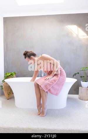 À la maison, femme en serviette préparant le bain dans un spa moderne, se relaxant et se détendre. Détente, bien-être, soins personnels, luxe, soins, tranquillité Banque D'Images