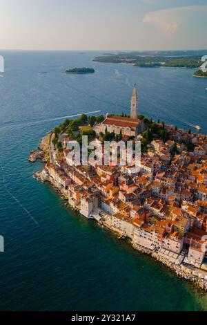 Nichée le long de l'Adriatique chatoyante, Rovinj captive avec ses bâtiments colorés et son église historique, créant une toile de fond pittoresque alors que le jour tourne au crépuscule, invitant à l'exploration et à la crainte. Banque D'Images