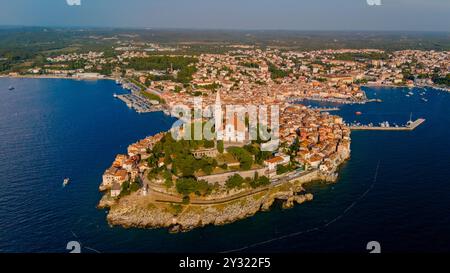 Alors que le soleil se couche sur Rovinj, les couleurs vibrantes se reflètent sur l'eau, soulignant l'architecture historique de la charmante ville et le paysage côtier époustouflant, invitant à l'exploration et à l'admiration. Banque D'Images