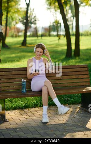 Une jeune femme se détend sur un banc, écoutant de la musique tout en profitant du plein air. Banque D'Images