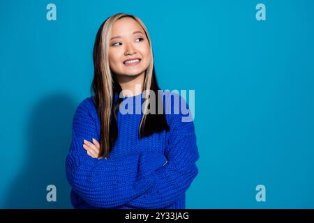 Portrait de cheveux teints jeune fille vietnamienne pliée mains satisfaites sourire semble confiant et réfléchi isolé sur fond de couleur bleue Banque D'Images