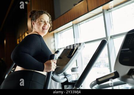 Une jeune femme aime son entraînement sur une machine elliptique, rayonnant de confiance et de positivité. Banque D'Images