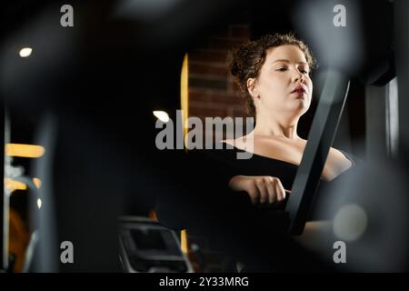 Une femme de grande taille s'entraîne en toute confiance, favorisant la positivité corporelle dans un cadre de gymnastique dynamique. Banque D'Images