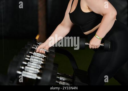 Une femme de grande taille s'entraîne en toute confiance, soulevant des haltères dans un environnement de gymnastique dynamique. Banque D'Images