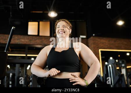 Une jeune femme aime son entraînement en tenue active, rayonnant positivité et confiance dans le gymnase. Banque D'Images