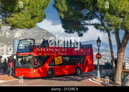 Bus touristique à arrêts multiples plein de personnes au départ de la place du Palais par une journée ensoleillée d'hiver, Principauté de Monaco Banque D'Images