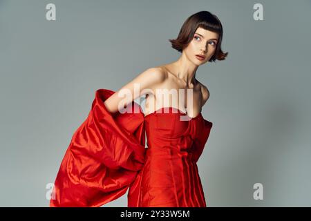 Une jeune femme met en valeur son style dans une robe rouge audacieuse avec un gros noeud. Banque D'Images