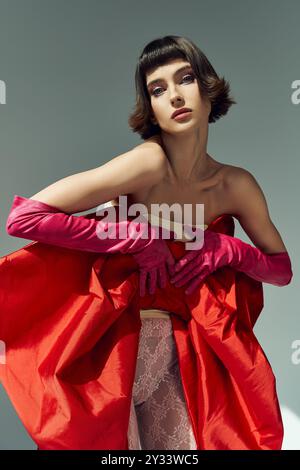 Une jeune femme montre son élégance dans une robe rouge audacieuse avec un arc dramatique. Banque D'Images