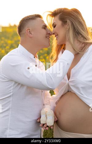 Couple heureux en tenue formelle souriant et embrassant dans un champ fleuri Banque D'Images