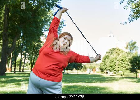 Une femme de grande taille aime s'étirer à l'extérieur dans un parc animé. Banque D'Images