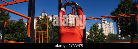 Une femme de grande taille aime l'exercice en plein air tout en s'étirant dans un parc animé. Banque D'Images