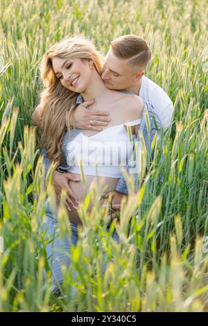 un homme embrasse une femme enceinte dans un champ de blé Banque D'Images