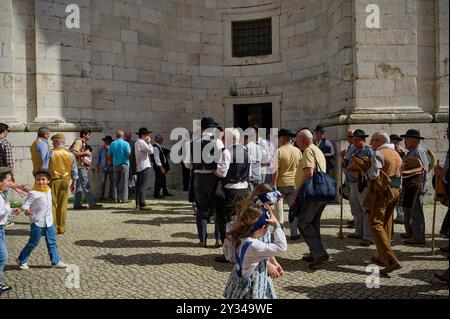 Un groupe d'hommes en tenue traditionnelle se réunit à l'extérieur du Panteão Nacional, tandis que les enfants marchent à travers la scène Banque D'Images