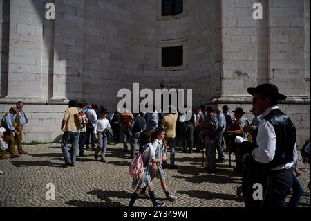 Un groupe d'hommes en tenue traditionnelle se réunit à l'extérieur du Panteão Nacional, tandis que les enfants marchent à travers la scène Banque D'Images